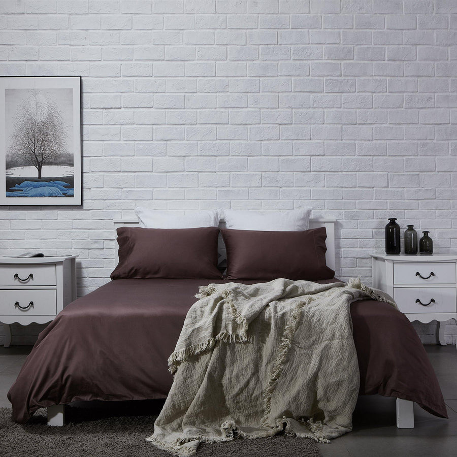 Full bedroom view with chocolate brown cotton sheet set and white brick wall