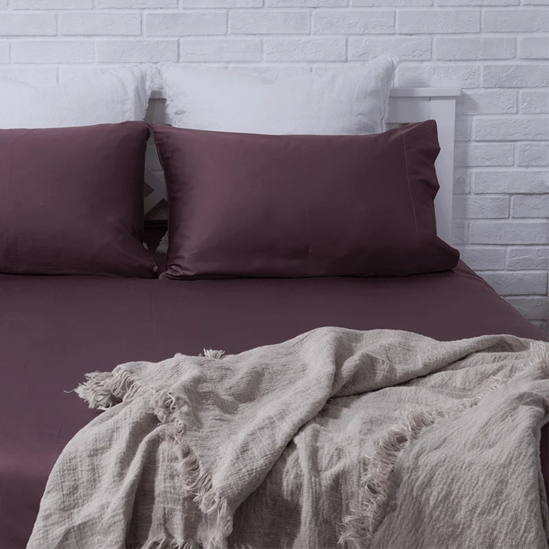 Folded chocolate brown cotton sheet set with pillowcases on white background